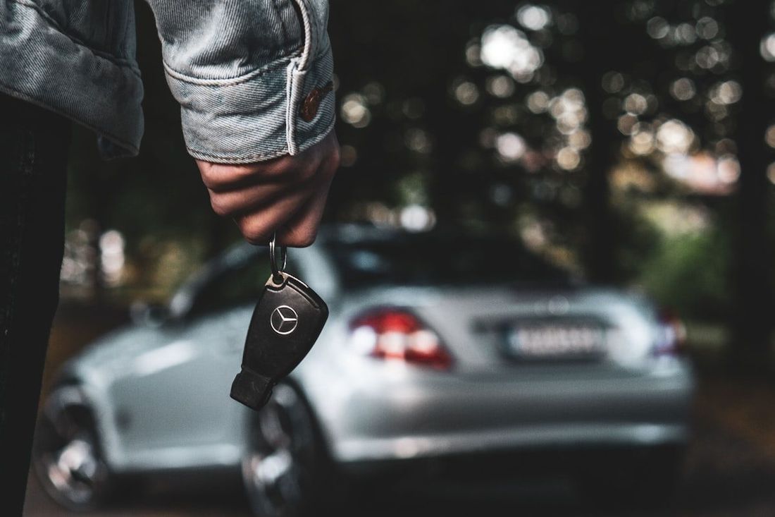 Car keys in hand with the car ready behind
